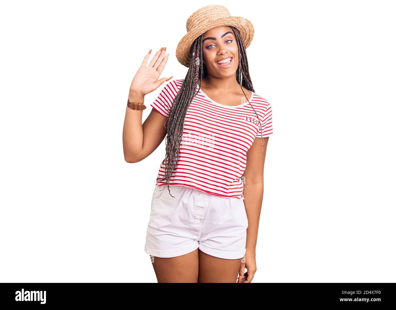 Junge afroamerikanische Frau mit Zöpfen tragen Sommerhut waiving sagen Hallo glücklich und lächelnd, freundliche Willkommensgeste Stockfoto