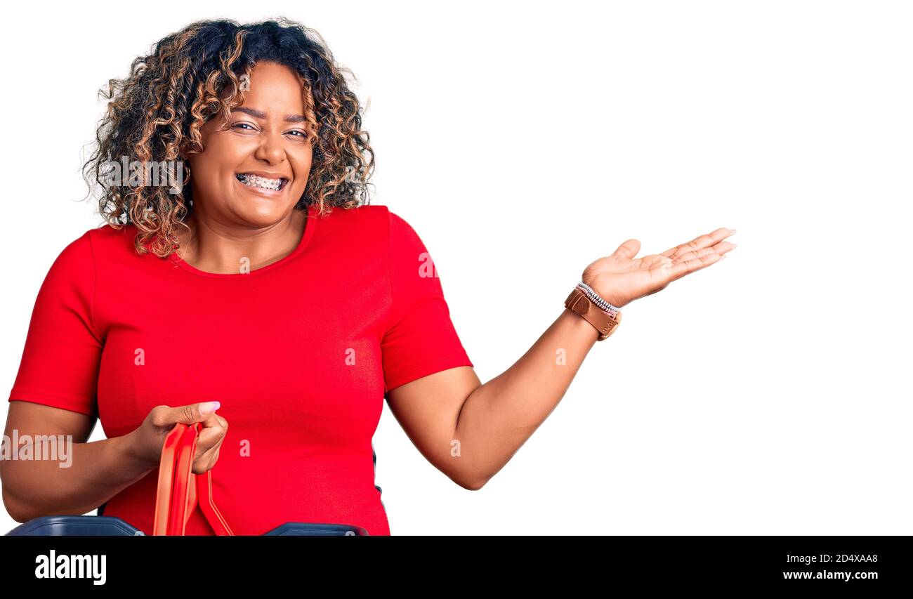 Junge afroamerikanische plus size Frau hält Supermarkt Warenkorb Feiern Sieg mit glücklichen Lächeln und Sieger Ausdruck mit raised Hand Stockfoto