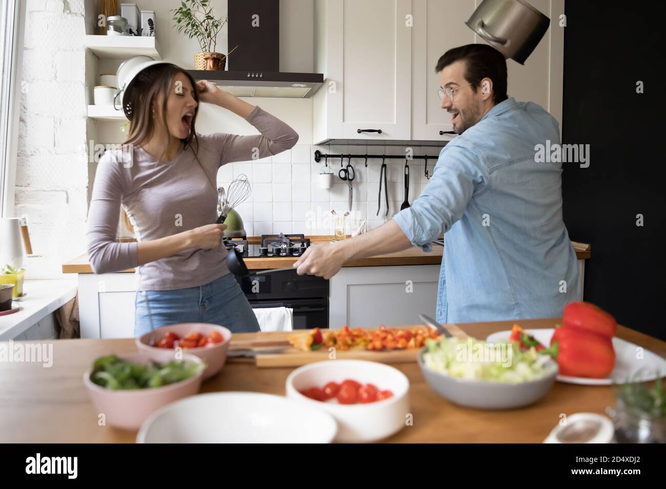 Überglücklich positives junges europäisches Familienpaar, das Spaß an der Küche hat. Stockfoto