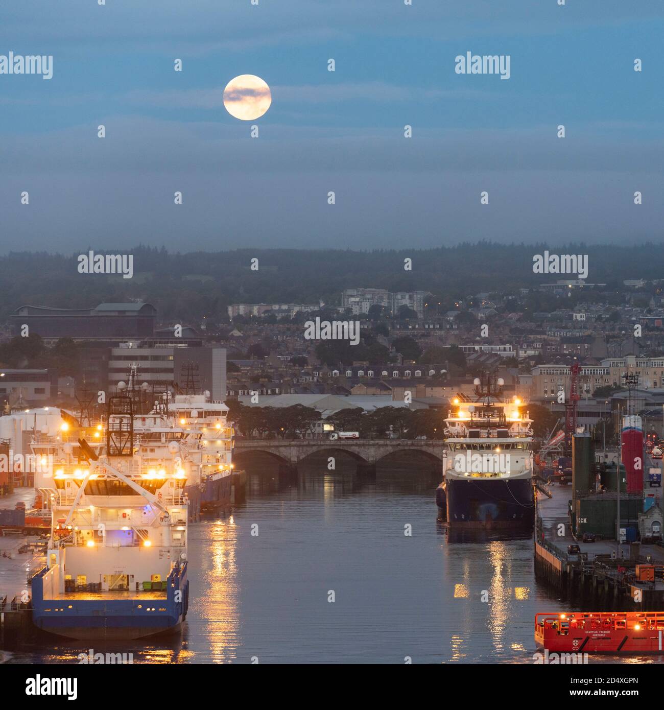 Ein Erntemond über Aberdeen's River Dee, mit Service-Schiffen für die Ölindustrie, die entlang der Quayside festgemacht wurden Stockfoto