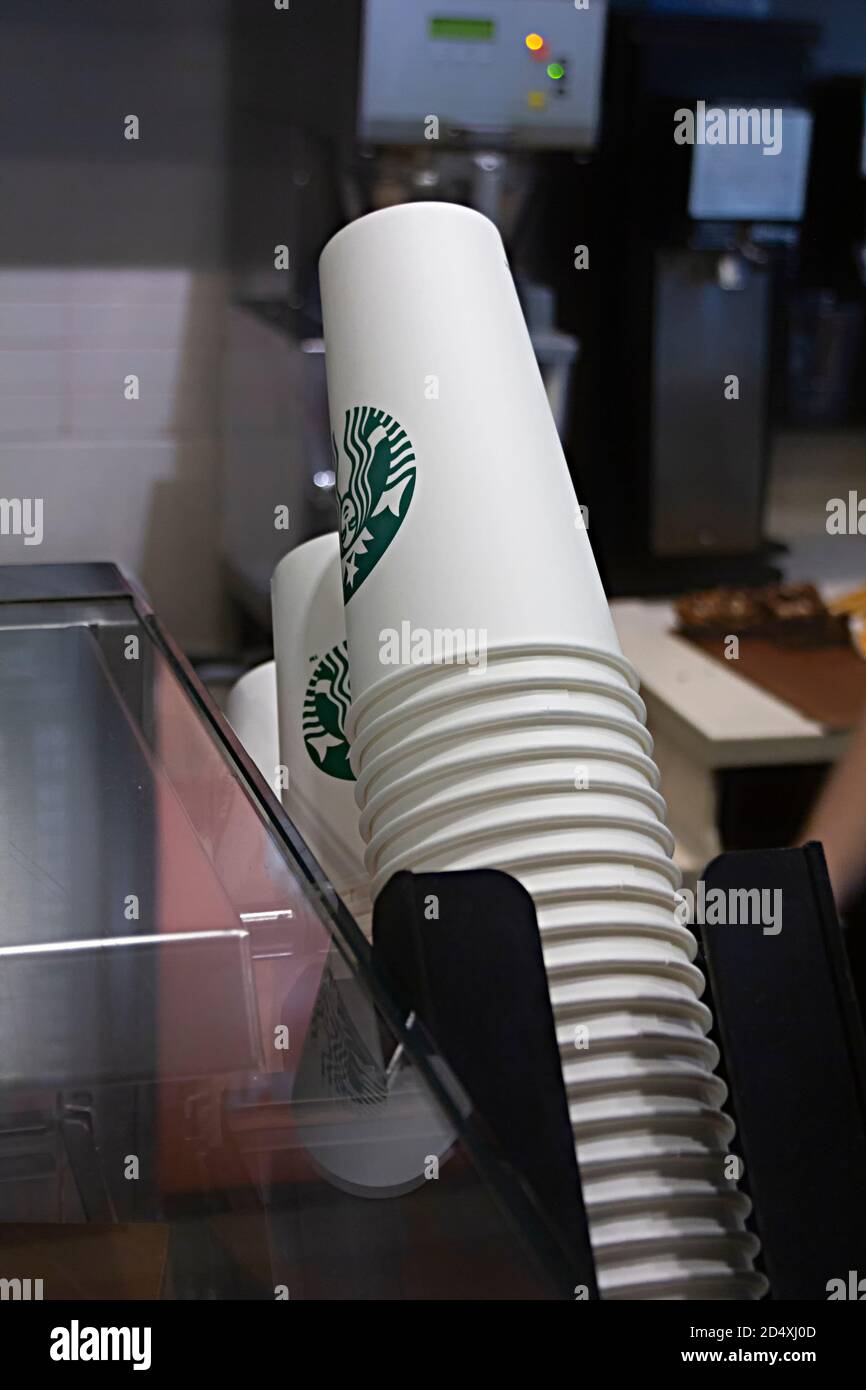 Saint-Petersburg, Russland - 03. OKTOBER 2020 Starbucks Einweg-Pappbecher stehen in der Nähe einer Kaffeemaschine und Kasse in einem Starbucks Café Stockfoto
