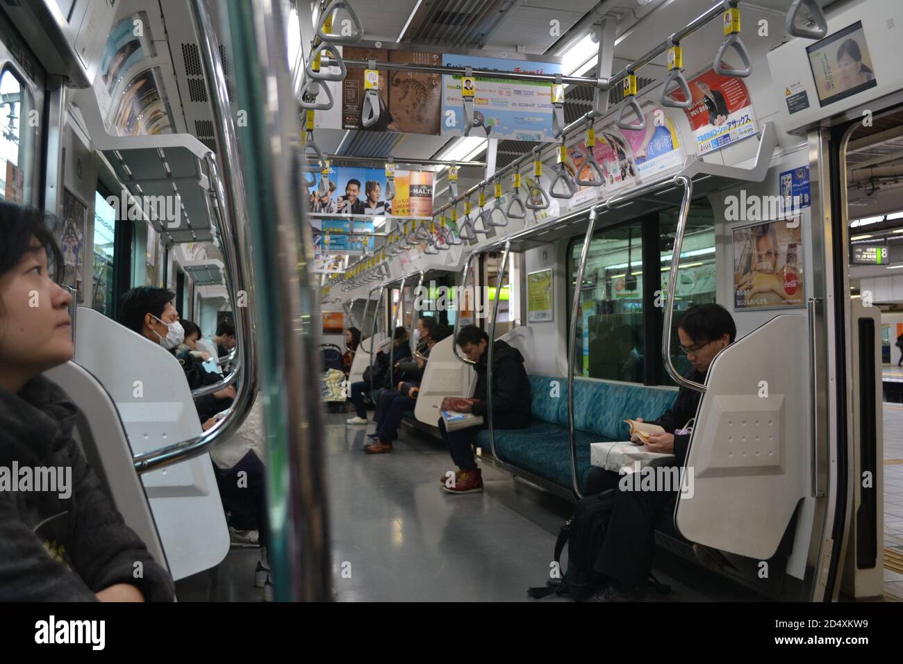 Tokyo, Japan-02/23/16: In einem lokalen Zug, der durch Tokyo fährt: Eine vielfältige Gruppe von Leuten, die auf ihren Zugsitzen sitzen sitzen und verschiedene Aktivitäten machen. Stockfoto