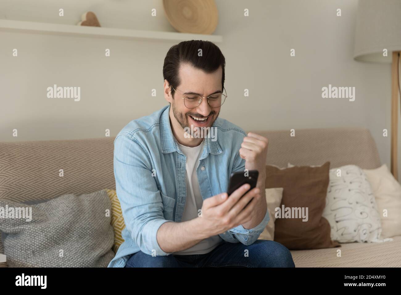 Junger glücklicher Mann liest sms mit guten Nachrichten. Stockfoto
