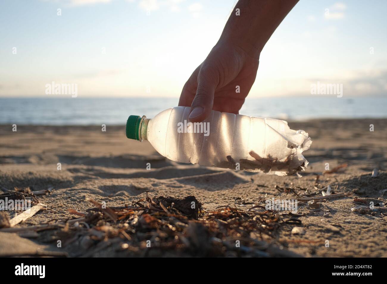 Mann Freiwillige sammeln Plastikflasche auf schmutzigen Meer Ökosystem, Umwelt kontaminiert Verschmutzung Stockfoto