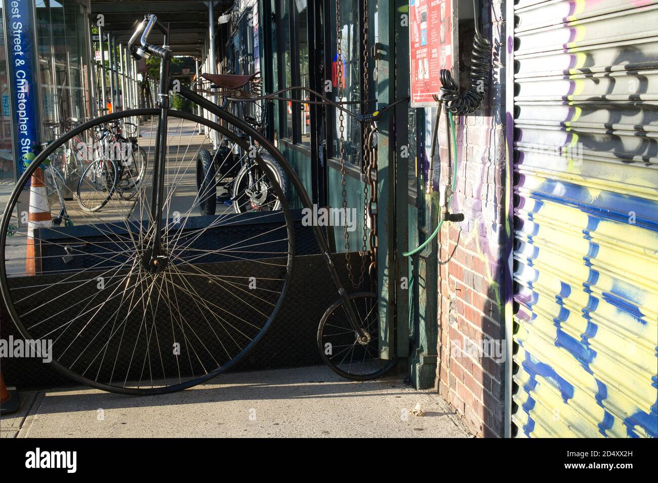 Antikes Fahrrad mit hohem Rad in einer Straße in Manhattan, an einen Fahrradladen angeschlossen Stockfoto