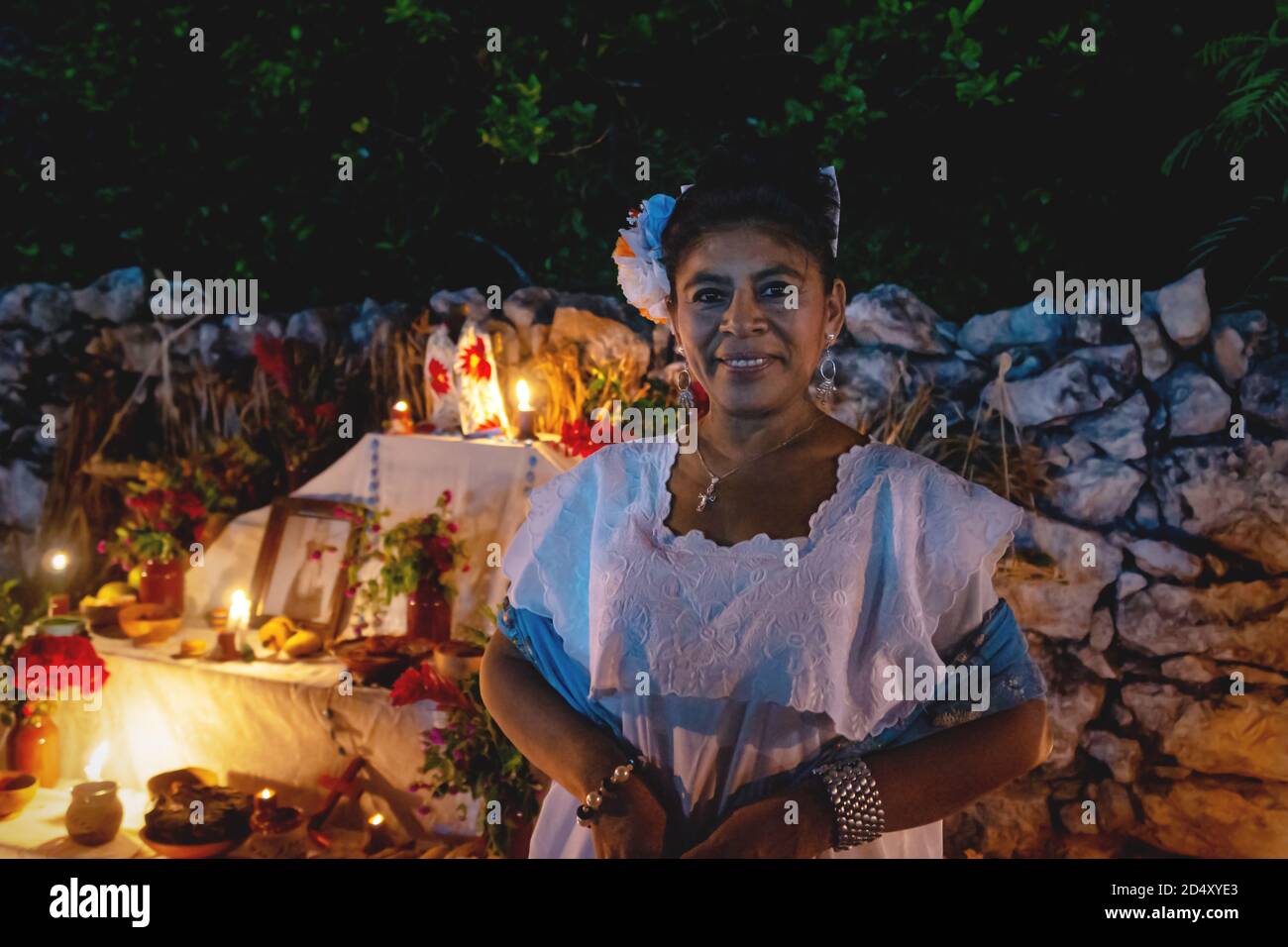 Merida, Mexiko - 31. Oktober 2018: Mexikanische Frau in traditioneller Kleidung vor dem Altar mit Opfergaben für den Tag der Toten 'Dia de los muertos', Meri Stockfoto