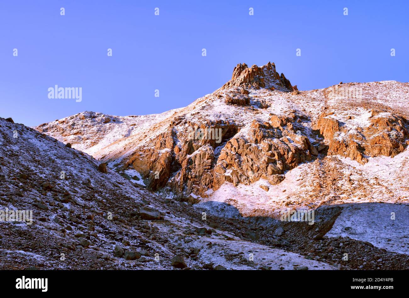 Kronenförmiger Fels mit Schnee bedeckt gegen einen blauen Himmel Im sanften Licht der Morgensonne Stockfoto