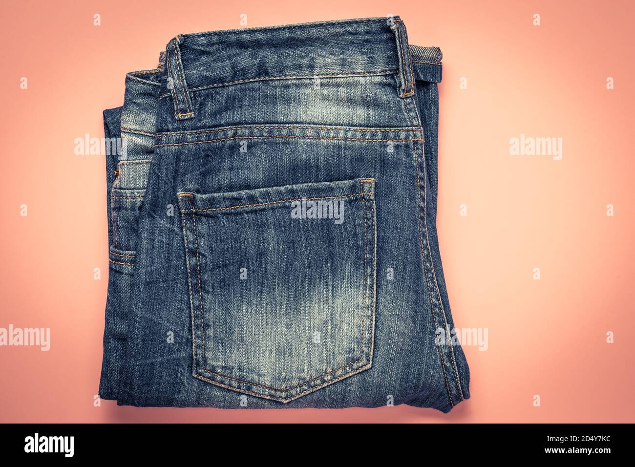 Blau ausgefranste Jeans mit Tasche, gefaltete Shabby Pants auf rosa Hintergrund. Dunkles Denim Stockfoto