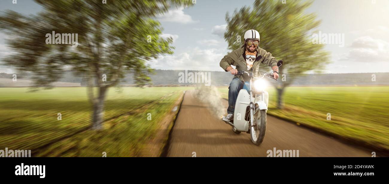 Mann mit seinem Hund auf einem Moped mit Höchstgeschwindigkeit Stockfoto