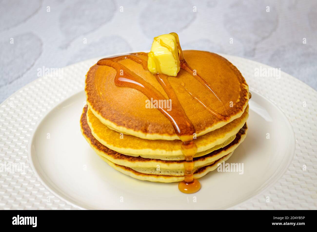 Lesen Sie, um süßen Pfannkuchen mit Honig und Butter garniert essen In einer runden Platte Stockfoto