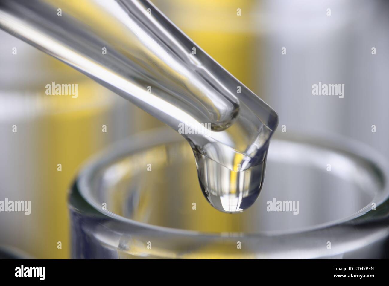 Chemischer Pipettenspender tropft gelbe Flüssigkeit in die Glaswaren in der Nähe Stockfoto