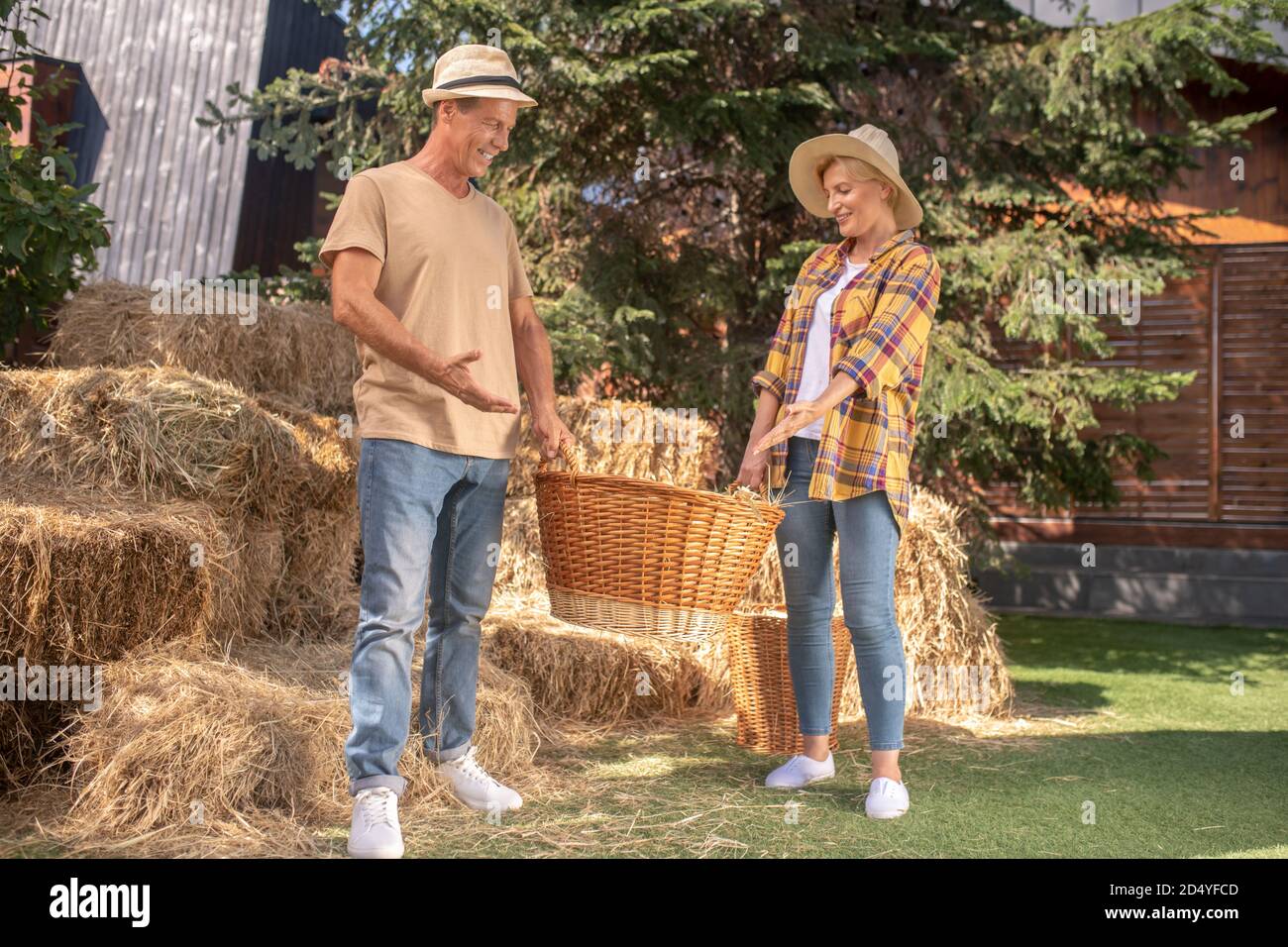 Männliche und weibliche Landwirte in der Holding Korb mit Koben, zeigt auf seinen Inhalt Stockfoto