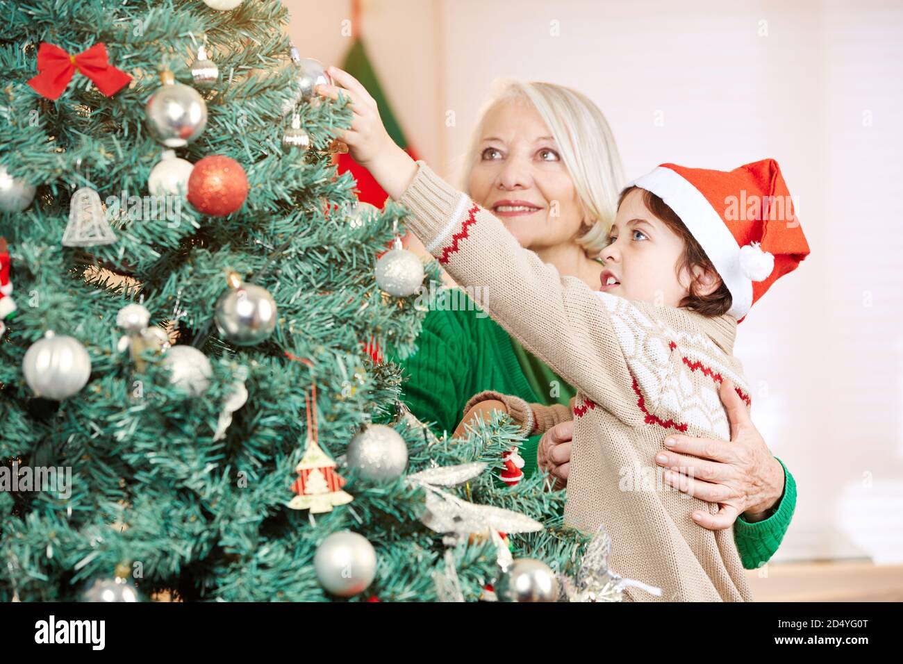 Großmutter und Enkel schmücken den Weihnachtsbaum zu Weihnachten zusammen Stockfoto