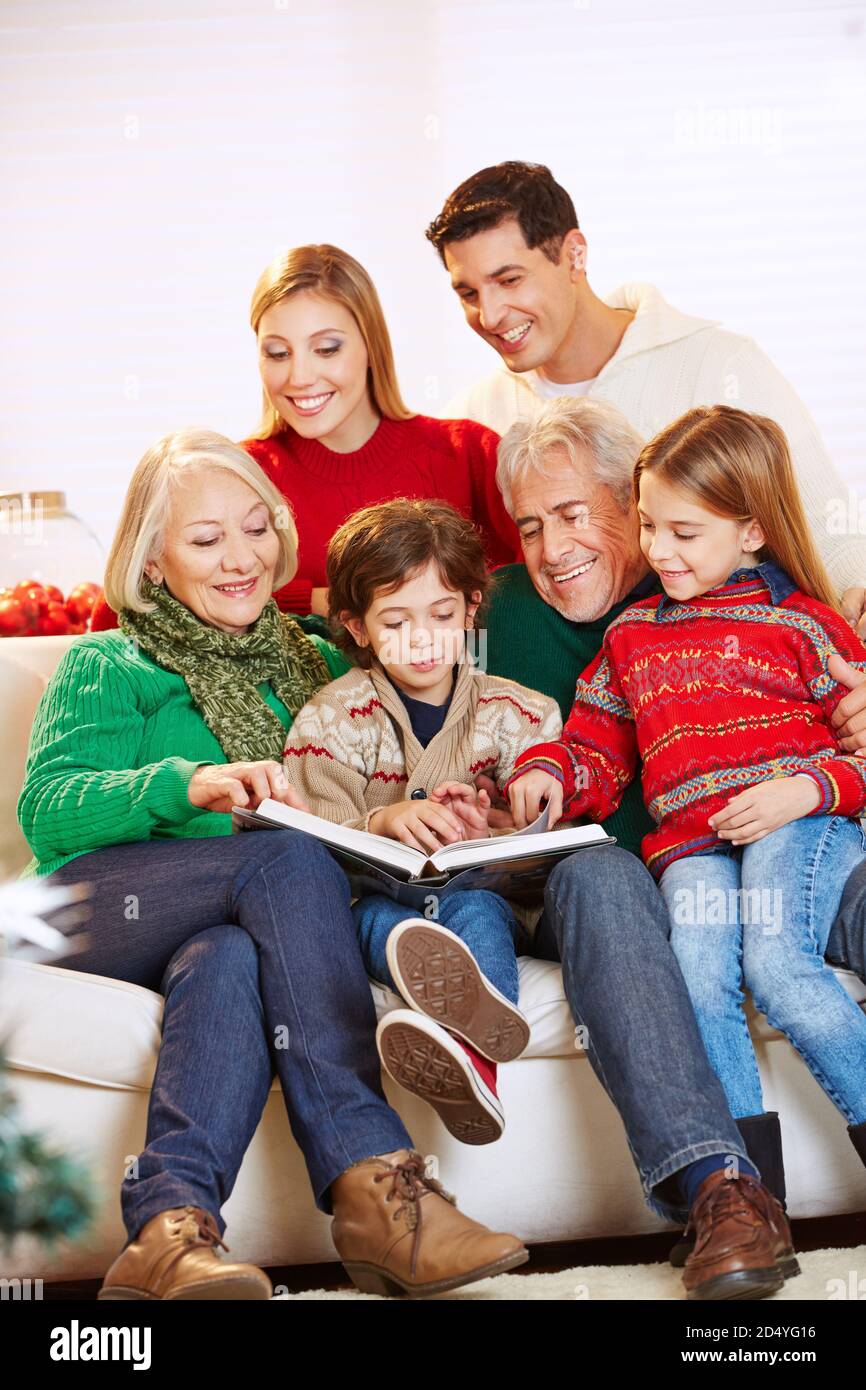 Glückliche Familie mit Großeltern, die zu Weihnachten ein Buch lesen Stockfoto