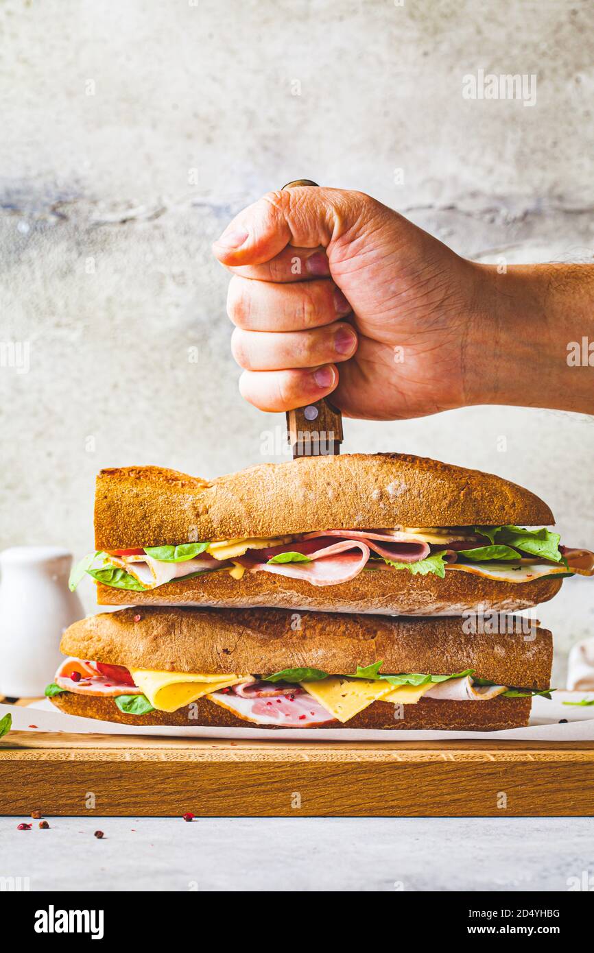 Baguette-Sandwich mit Fleisch, Käse und Gemüse auf einem Holzbrett. Stockfoto