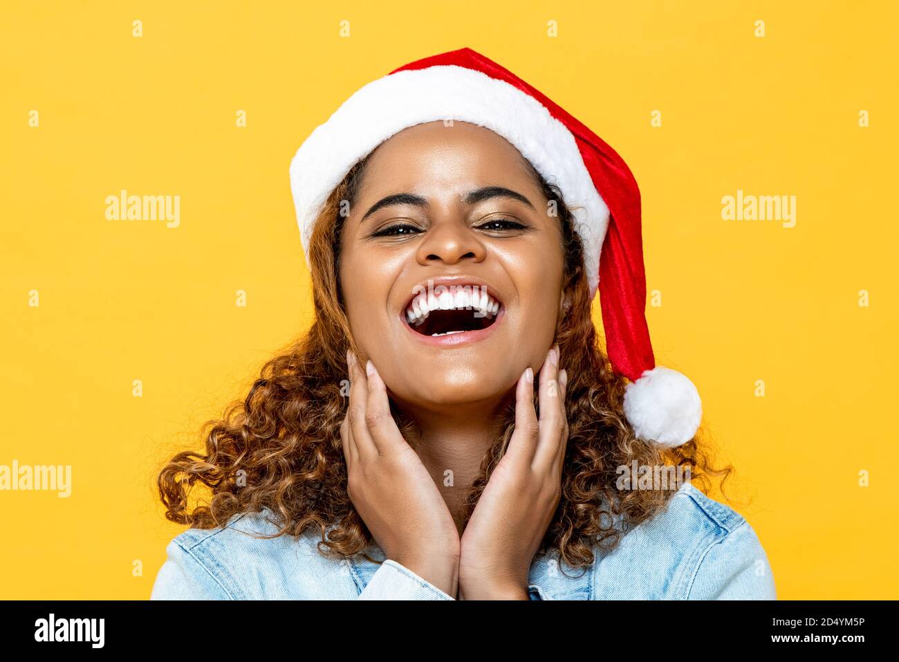 Nahaufnahme Porträt von erstaunt glücklich afroamerikanischen Frau tragen Weihnachtsmütze lächelnd auf gelbem isoliertem Hintergrund Stockfoto