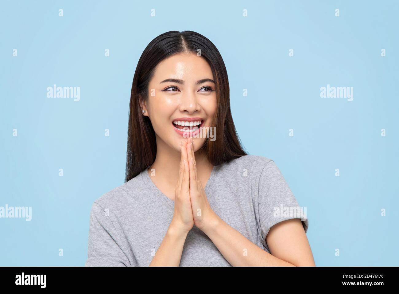 Lächelnd schöne asiatische Frau tun Wai Geste für Gruß oder Danke isoliert auf hellblauem Hintergrund Stockfoto