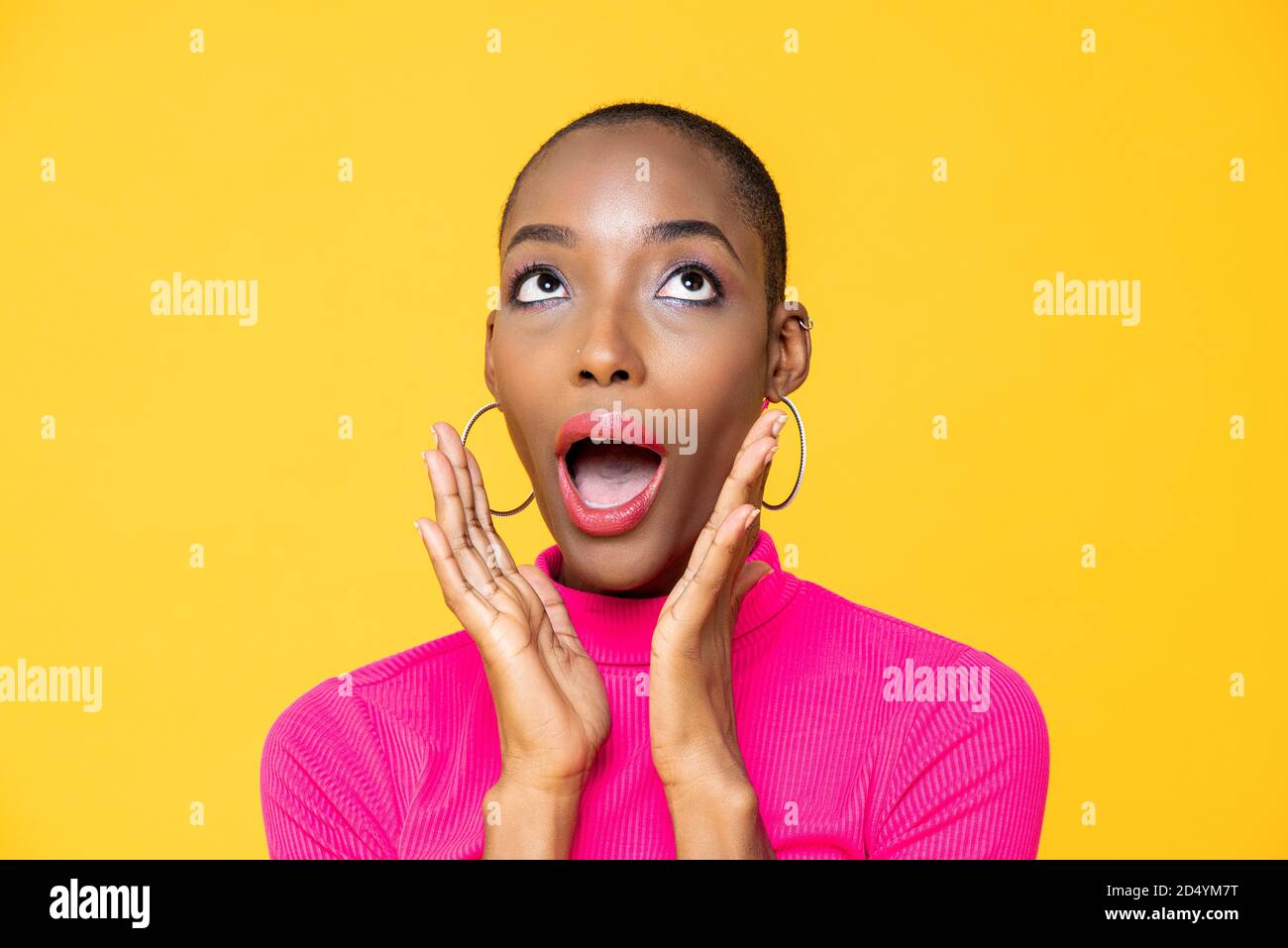 Nahaufnahme Porträt der überrascht junge afroamerikanische Frau suchen Nach oben mit den Händen rund um den Mund isoliert auf Studio gelb Hintergrund Stockfoto