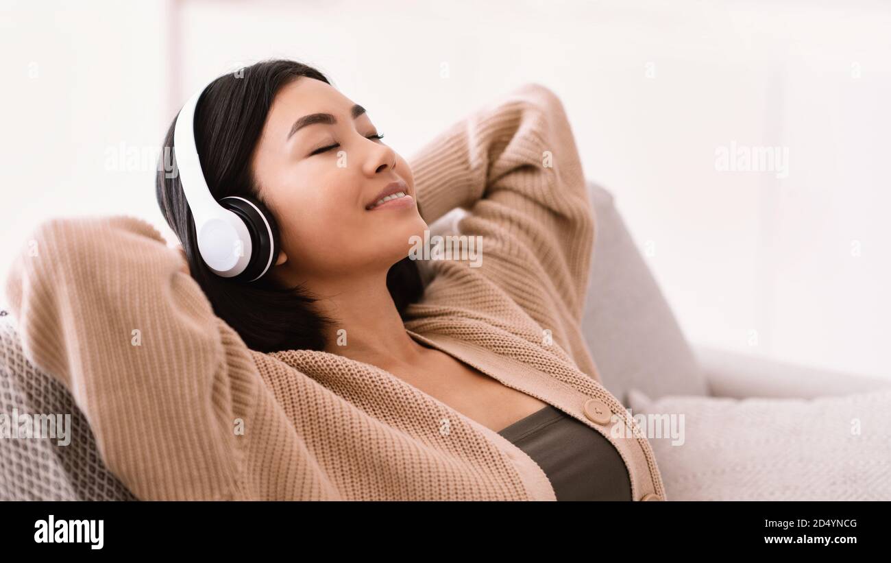 Asiatische Frau, die mit Kopfhörern Musik hört Stockfoto