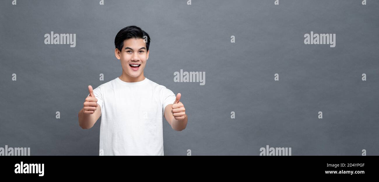 Schöner asiatischer Mann lächelt und gibt Daumen nach oben auf grau Isolierter Banner-Backround mit Kopierbereich Stockfoto