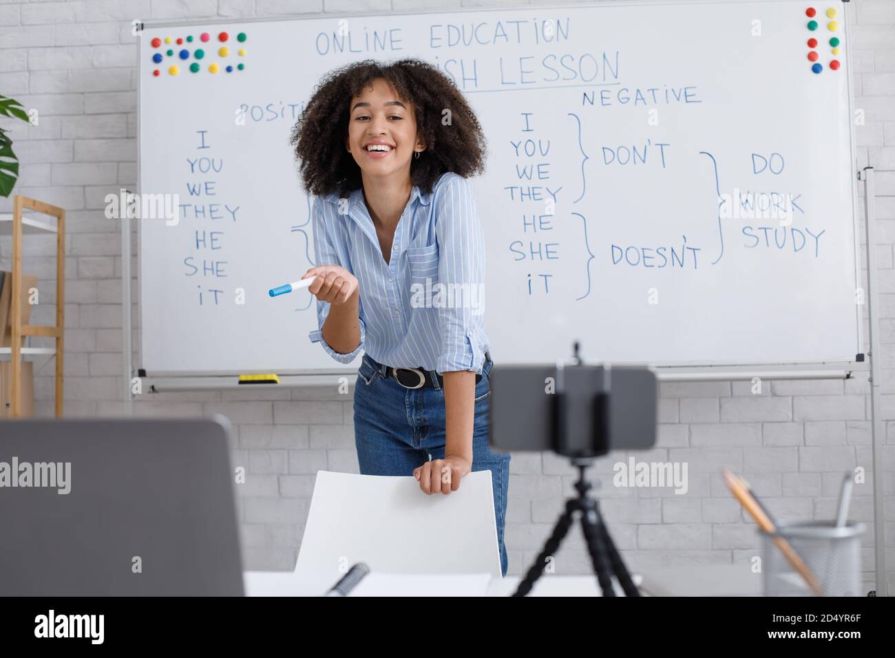 Spaß Englischunterricht und Video-Streaming. Lachende afroamerikanische Dame steht in der Nähe des Whiteboards mit Regeln Stockfoto