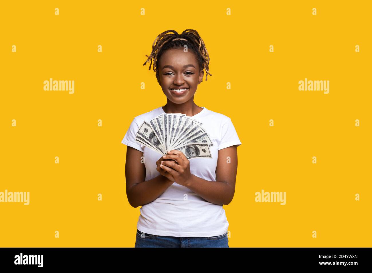 Glückliche schwarze Frau hält Geld auf gelbem Hintergrund Stockfoto