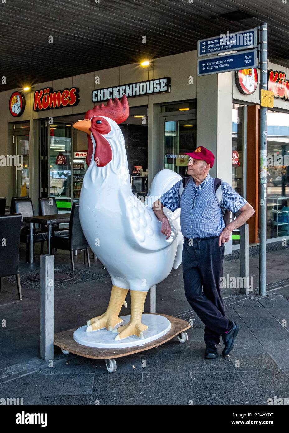 Älterer, älterer Mann, der neben dem Modell des Hühners vor dem Kümes Hühnerstall Fast Food Outlet, Kuhligkshofstraße 2, Steglitz-Berlin, steht Stockfoto