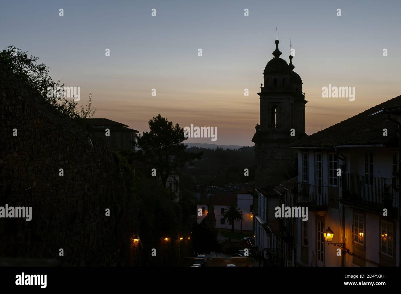 Santiago de Compostela, Galicia, Spanien - 09/27/2020: Convento de San Francisco bei Sonnenuntergang mit einer schwach sitzigen Straße & Stadthäusern davor. Sonnenuntergang in Spanien Stockfoto