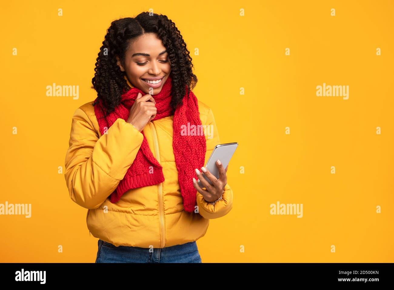 African American Lady Holding Phone Reading Mobile Nachrichten, Yellow Background Stockfoto