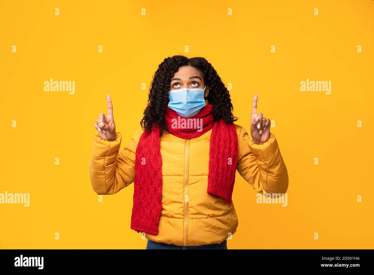 Schwarze Frau Im Gesicht Maske Zeigt Finger Nach Oben, Gelber Hintergrund Stockfoto