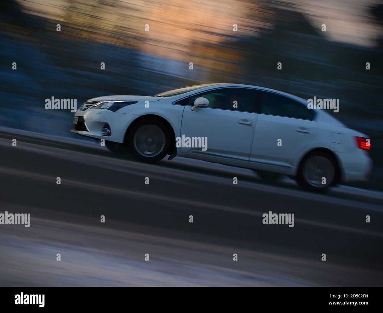 Ein schneeweißer Toyota Avensis fährt an einem kalten Winterabend in Finnland Stockfoto