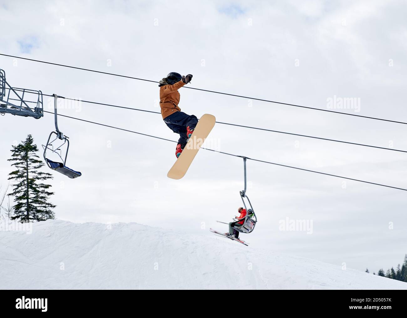 Guy Snowboarder macht Tricks in den Bergen in der Wintersaison, fliegen hoch mit Snowboard gegen Skilift und bewölkten Himmel. Low-Angle-Ansicht. Konzept der Winter Arten von Sport, Extremsport. Stockfoto