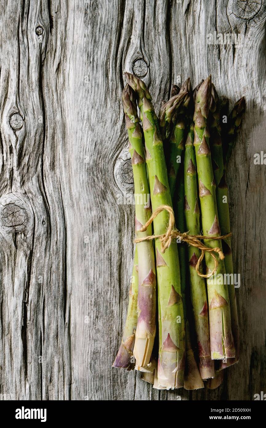 Bündel von raw Organic Green Spargel über alte Holz- Hintergrund. Flach, Raum Stockfoto