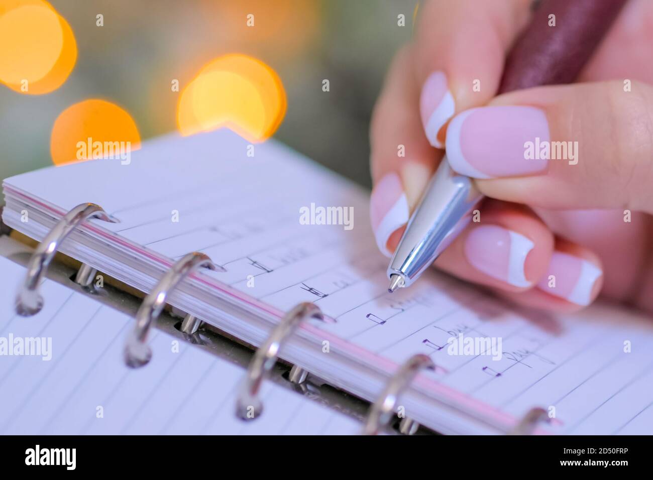 Frau Hand setzen markieren Sie die Kontrollkästchen der To-do-Liste in Personal Notebook Organizer. Girlande Licht Bokeh Hintergrund. Weihnachten, Motivation, Management Stockfoto