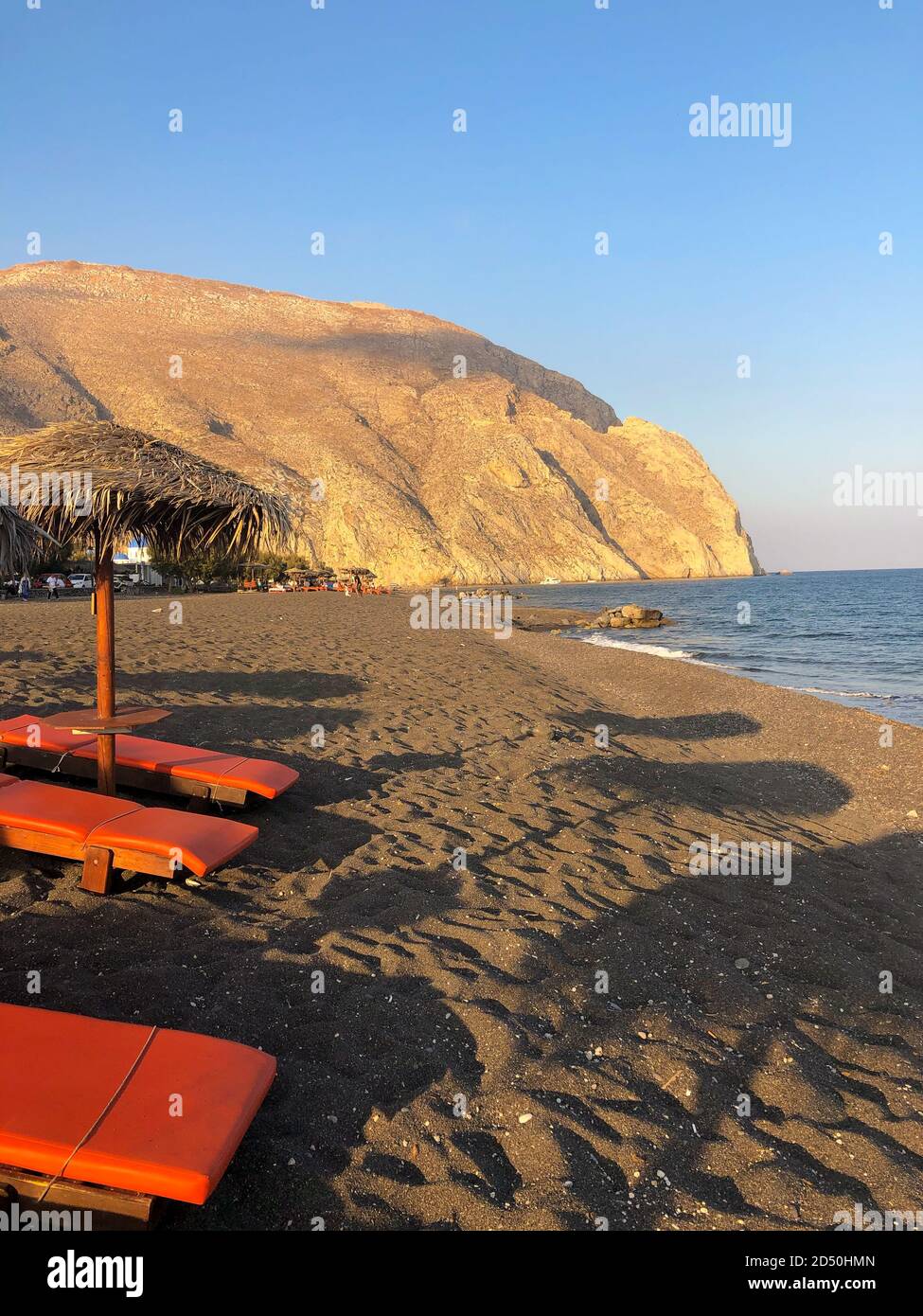 Schöner schwarzer Sandstrand von Perissa, auf der Insel Santorini in Griechenland, bei Sonnenuntergang. Stockfoto