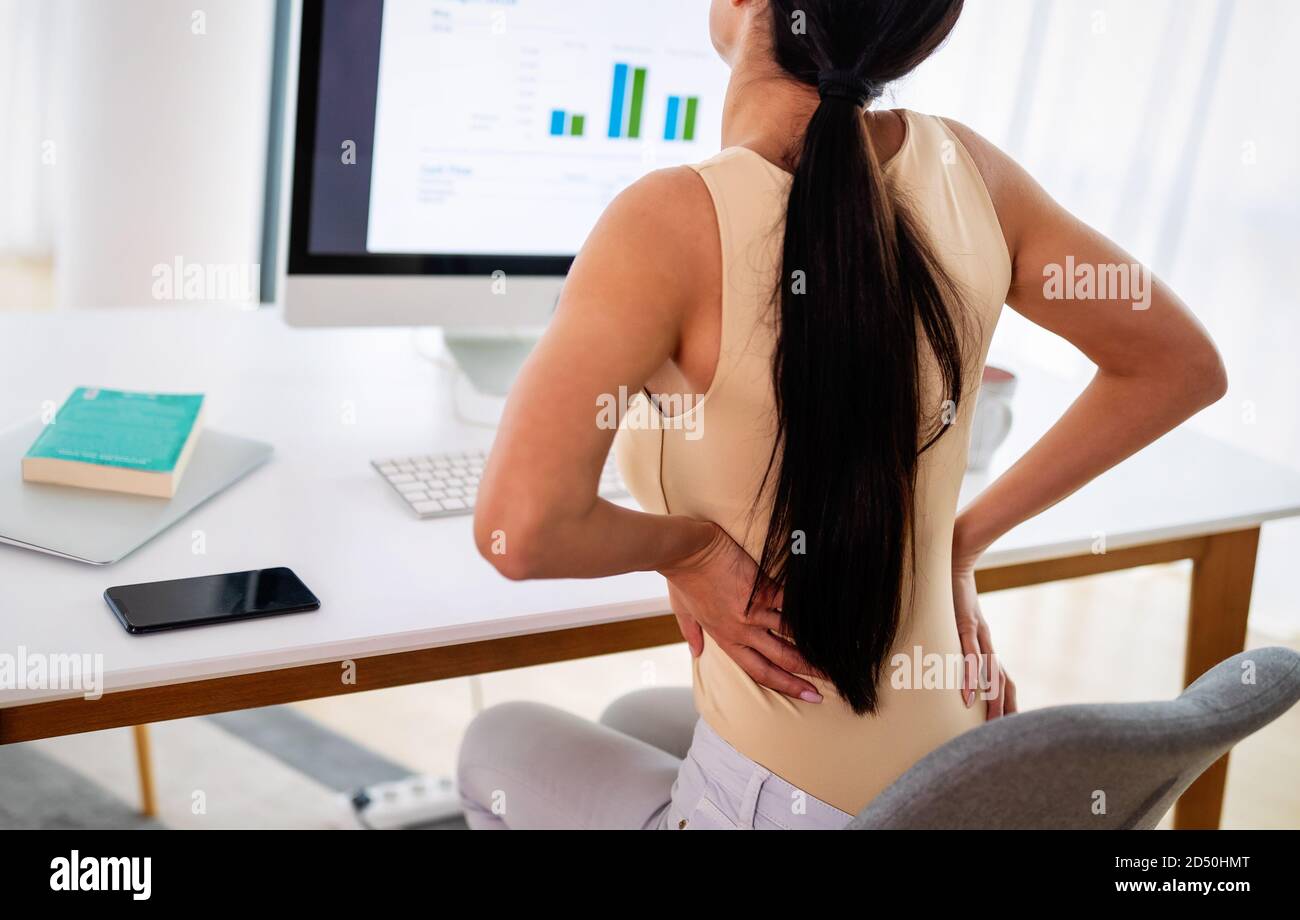 Überforderten Frau mit Rückenschmerzen im Büro mit schlechter Haltung Stockfoto