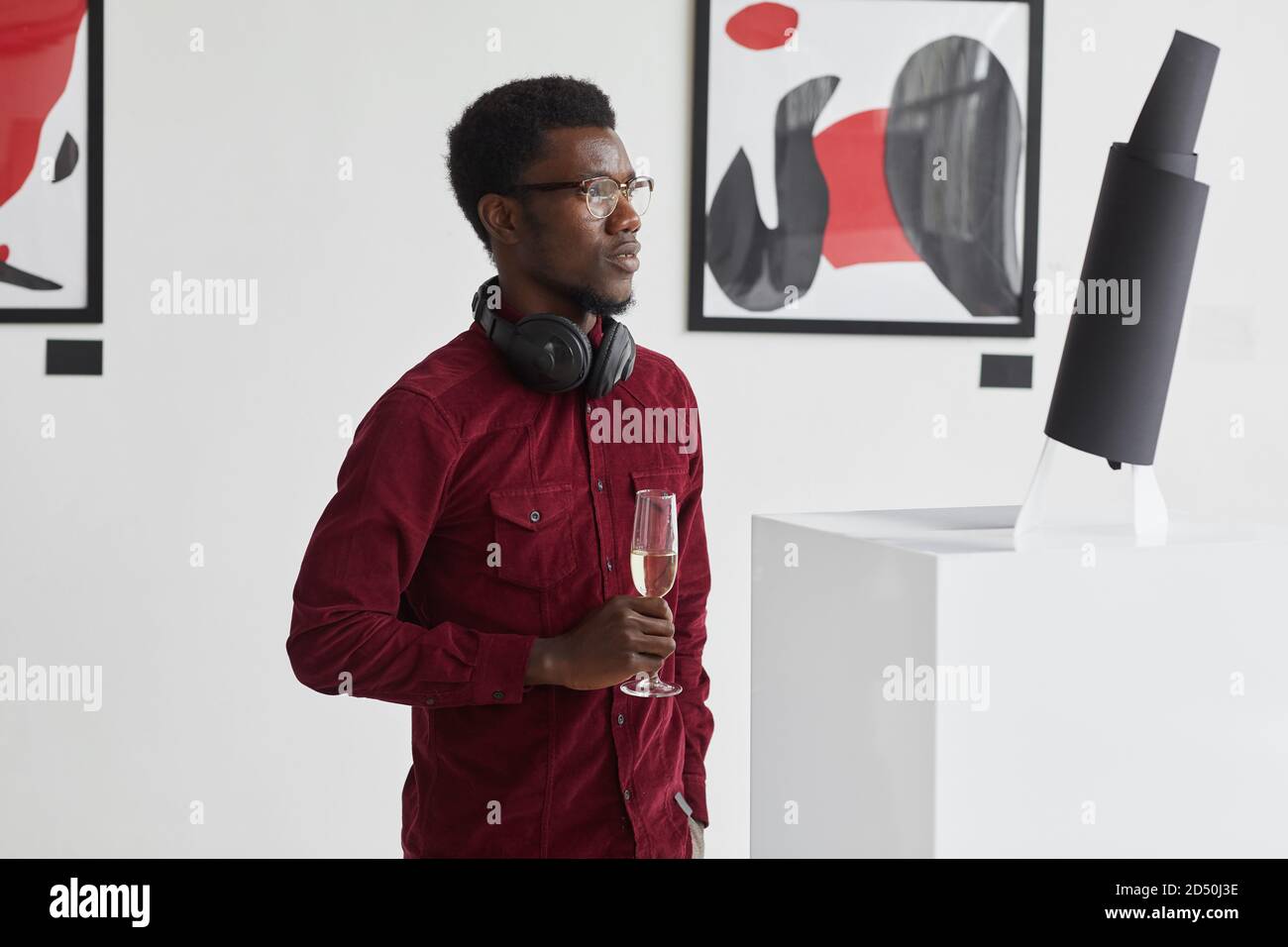 Waist up Porträt des modernen afroamerikanischen Mann hält Champagner Glas während der Erkundung der modernen Kunstgalerie Ausstellung, Copy Space Stockfoto