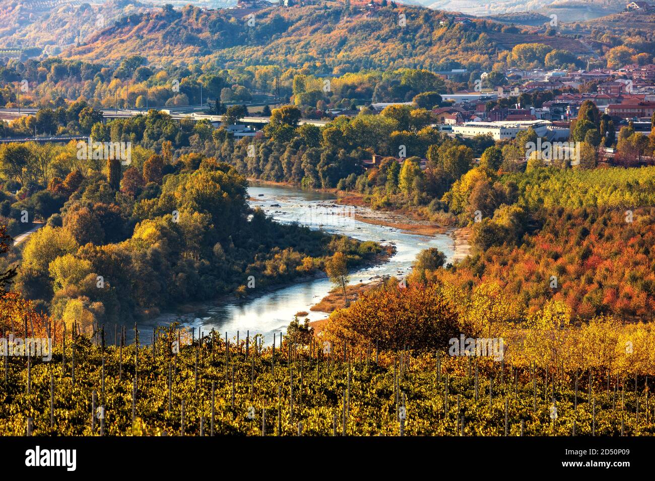 Blick von oben auf den Fluss Tanaro unter bunten Herbstbäumen in der Nähe der Stadt Alba im Piemont, Norditalien. Stockfoto