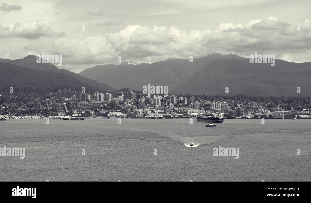 Blick auf den Hafen von Vancouver in Kanada, vom Wasser aus gesehen. Mit Frachtschiffen, Hochhäusern und rollenden Bergen im Hintergrund. Stockfoto