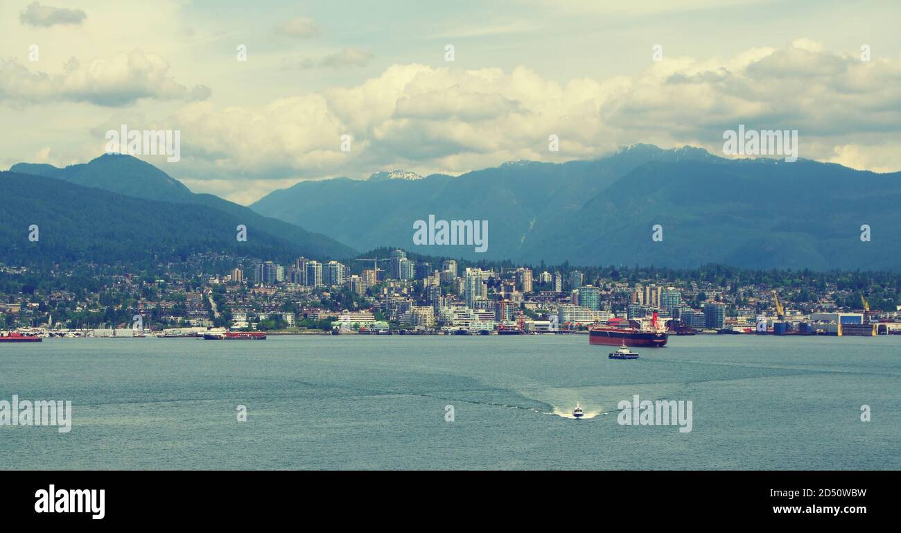 Blick auf den Hafen von Vancouver in Kanada, vom Wasser aus gesehen. Mit Frachtschiffen, Hochhäusern und rollenden Bergen im Hintergrund. Stockfoto