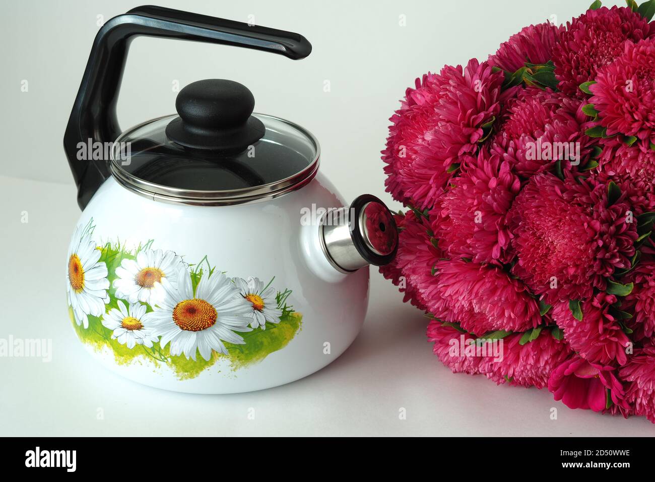 Emaillierte Utensilien. Schöner weißer emaillierter Wasserkocher mit Pfeife und Muster. Stockfoto