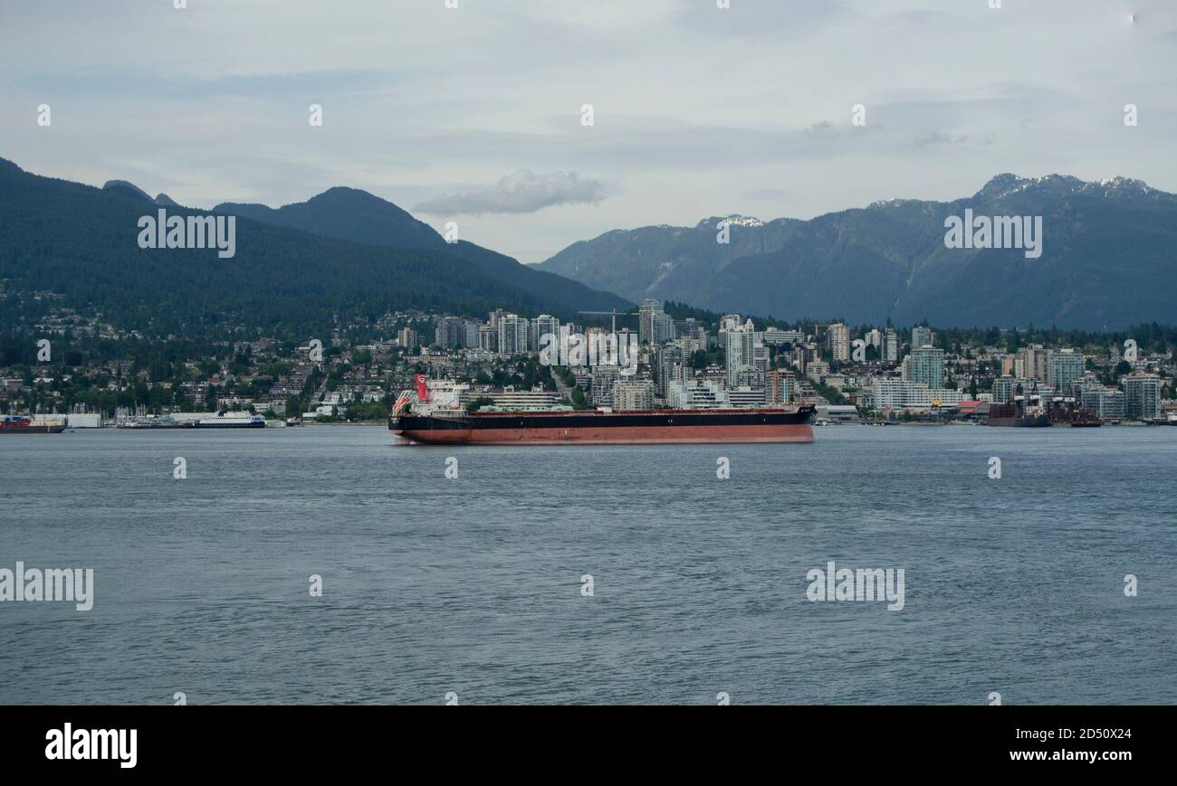 Ein großes Frachtschiff im Vancouver Port of Canda, mit Vancouver im Hintergrund. Stockfoto