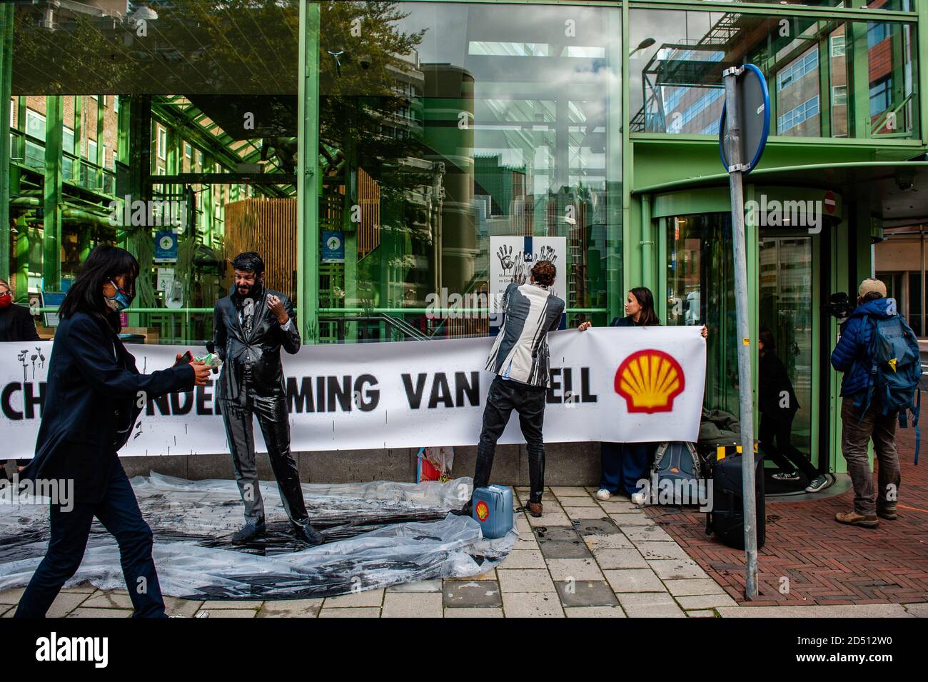 Mehrere Klimaaktivisten sahen, wie sie Handdrucke von gefälschtem Öl an der Fassade hinterließen.das Wirtschaftsministerium (EZK) organisiert einen Klimatag mit dem Ziel, die Niederlande mit "Spitzenreitern" zu inspirieren, die Treibhausgasemissionen bis 2030 zu halbieren. Verschiedene Klimagruppen protestieren gegen die Teilnahme von Marjan van Loon, Direktor von Shell Netherlands. Im Eröffnungspanel des Klimatages. Mehrere Klimaorganisationen tauchten vor dem Gebäude des Ministeriums für Wirtschaft und Klimapolitik in Den Haag gegen Shell als Ehrengast am "Klimatag" auf. Das Klima Stockfoto
