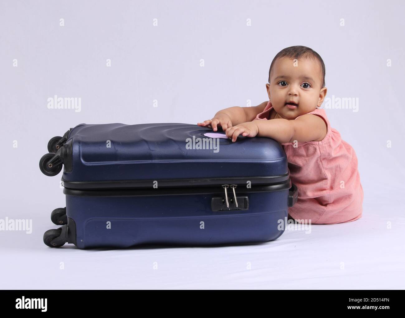 Reisen, Kinder, Urlaub - Lustiges Baby Mädchen neben geschlossenen Koffer sitzen. Stockfoto