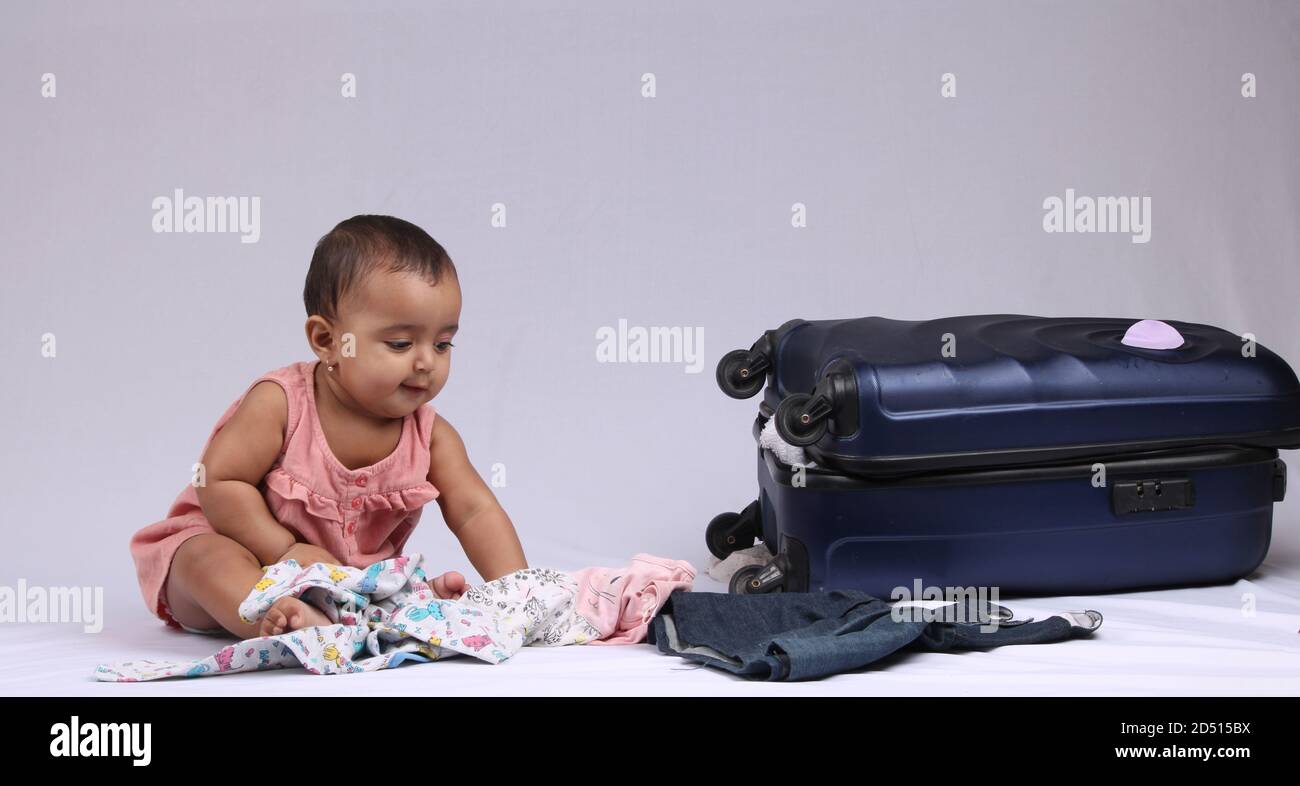 Reisen, Kinder, Urlaub - Lustiges Baby Mädchen neben geschlossenen Koffer sitzen. Stockfoto