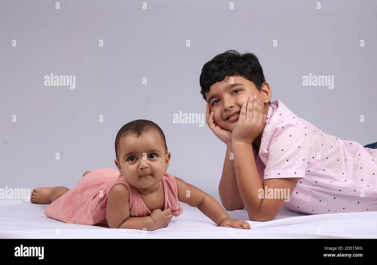 Niedlichen kleinen Jungen spielt mit seiner jüngeren Schwester zu Hause liegt auf weißen Hintergrung. Stockfoto