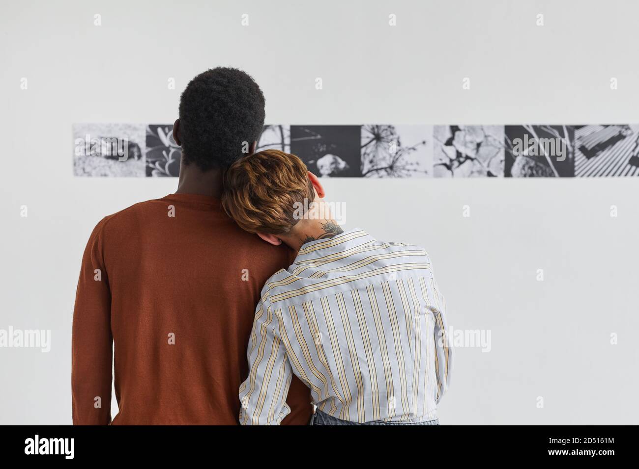 Rückansicht Porträt von Mischvolt-Paar umarmen, während Blick auf Gemälde in der modernen Kunstgalerie Ausstellung, copy space Stockfoto