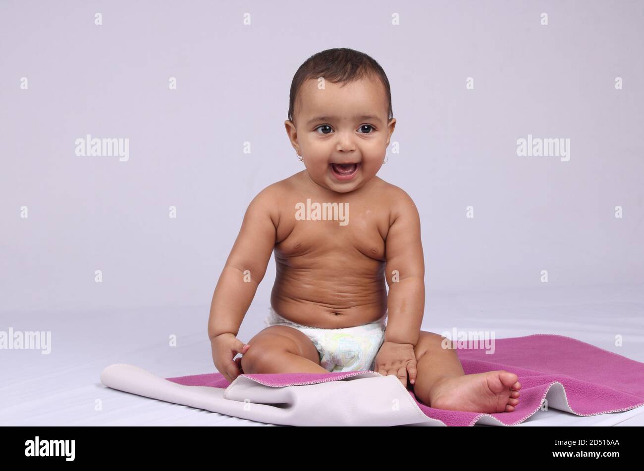 Glücklich aussehendes indisches Baby, das in einer Windel sitzt, nachdem es Öl massiert wurde. Stockfoto