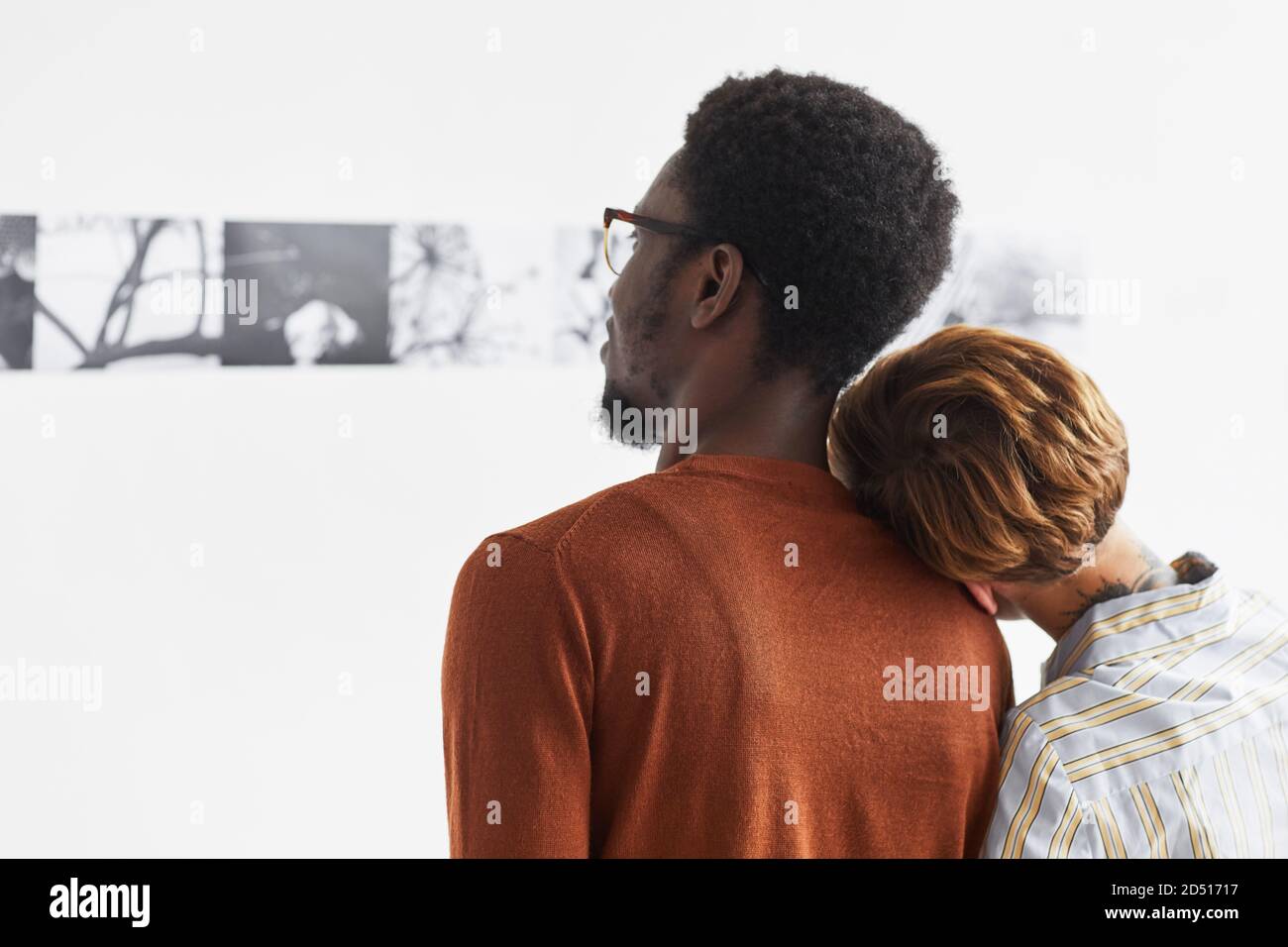 Grafisches Porträt eines Mischvolk-Paares umarmt beim Blick auf Gemälde in der modernen Kunstgalerie Ausstellung, Copy Space Stockfoto