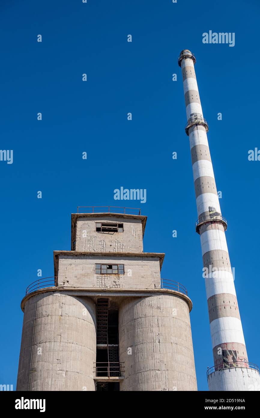 Alte verlassene Industrieanlage. Betonsilos und Schornstein in der Düngemittelfabrik. Drapetsona Piräus Griechenland, blauer Himmel, sonniger Tag. Stockfoto